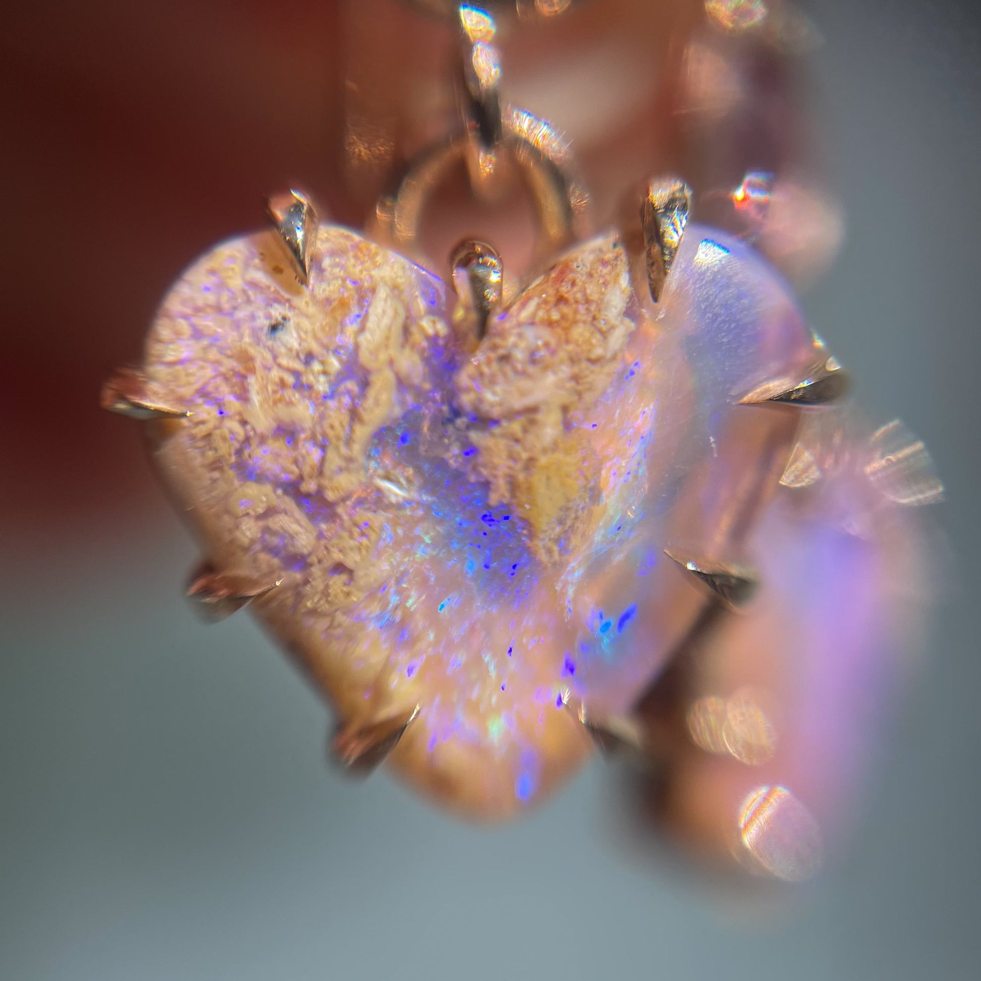 Close up shot of a pair of Australian Opal Earrings by NIXIN Jewelry. The opal heart earrings are in a claw setting.