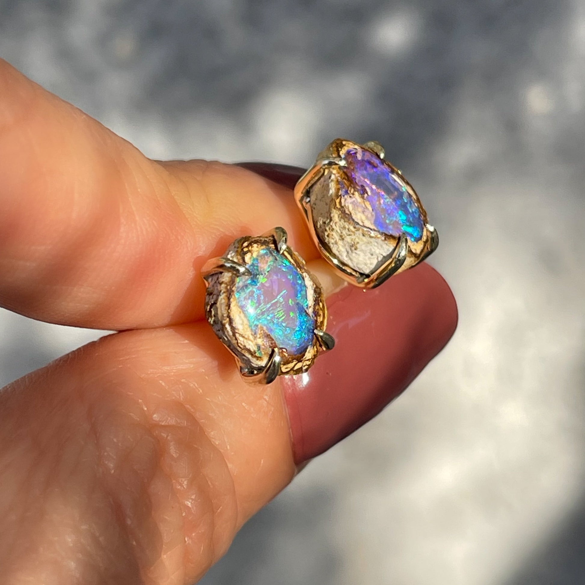 Angled shot of a pair of Australian Opal Earrings by NIXIN Jewelry. Natural opals in prong setting.