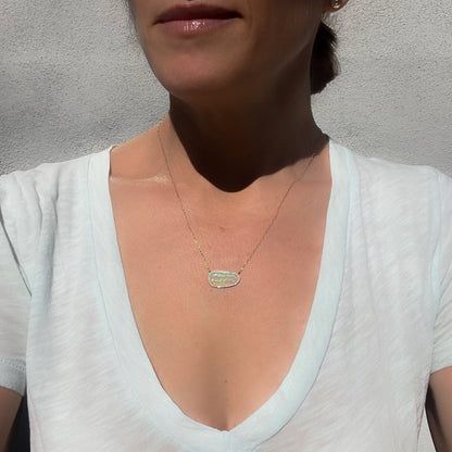 A model wearing an Australian Opal Necklace by NIXIN Jewelry with pave diamonds to show scale.