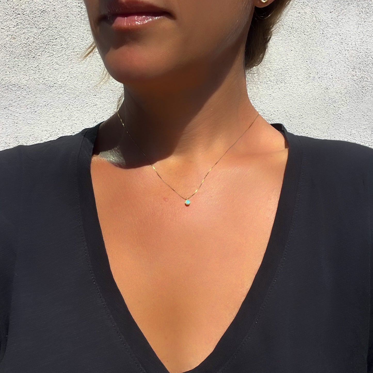 An Australian Opal Necklace by NIXIN Jewelry modeled on a woman. The Crystal Opal Necklace is made in yellow gold and is 16" long.