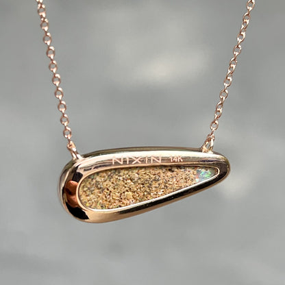 The back of an Australian Opal Necklace by NIXIN Jewelry. The picture shows the rose gold bezel setting that the opal stone rests in.
