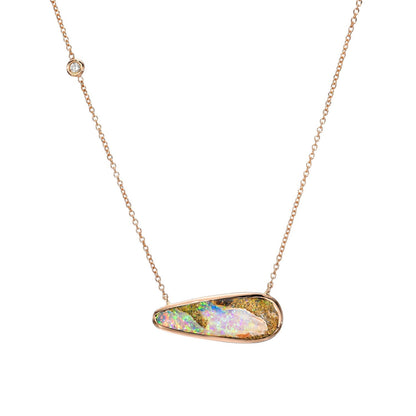 An Australian Opal Necklace by NIXIN Jewelry hangs in front of a white backdrop. The rose gold opal necklace has a pipe opal and sparkling diamond.