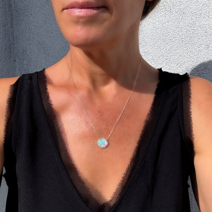 An Australian Opal Necklace by NIXIN Jewelry, visibly worn by a woman for clear scale and fit. This gold opal necklace features an elegant opal pendant necklace with a diamond halo. A stunning women's luxury necklace that elevates any outfit with its unique design.