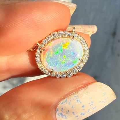 An Australian Opal Necklace by NIXIN Jewelry, highlighting the intense fire and play-of-color in the natural crystal opal stone. The opal pendant is secured in a prong setting surrounded by pave diamonds. This unique opal jewelry is a perfect representation of rare opal jewelry.