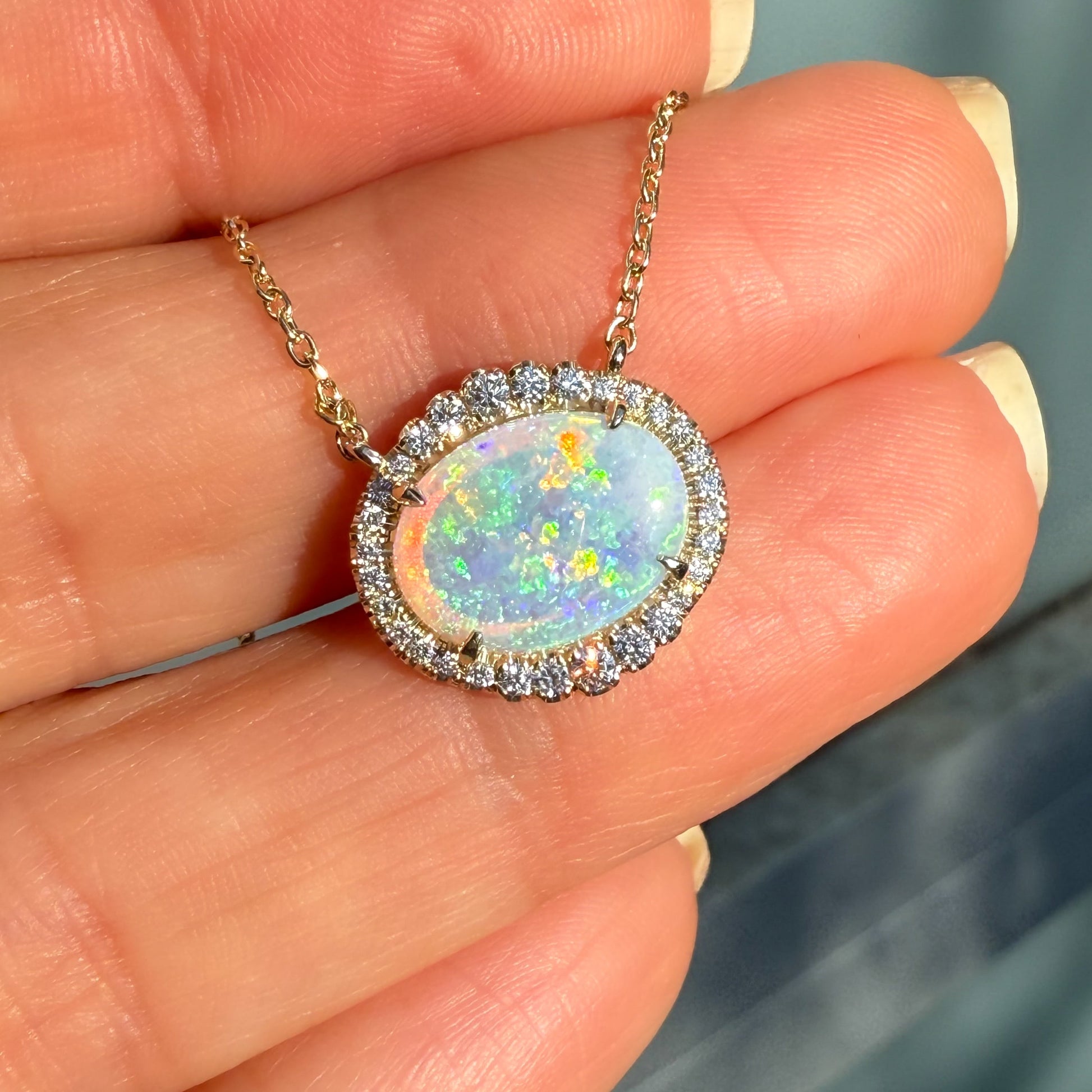 An Australian Opal Necklace by NIXIN Jewelry, featuring a truly one-of-a-kind Australian opal. The opal pendant is surrounded by a dazzling diamond halo in a secure prong setting. This women's luxury necklace combines the beauty of opals and diamonds into rare opal jewelry.