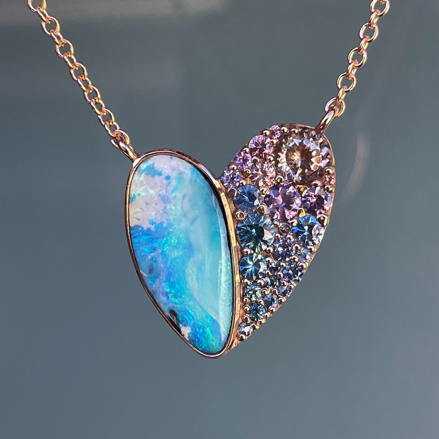 A Heart Opal Necklace by NIXIN Jewelry made in 14k rose gold with an opal and sapphire pendant.