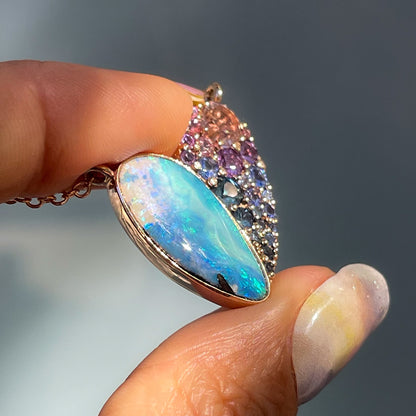 Side view of a Heart Opal Necklace by NIXIN Jewelry with a bezel set opal and pave set sapphires.