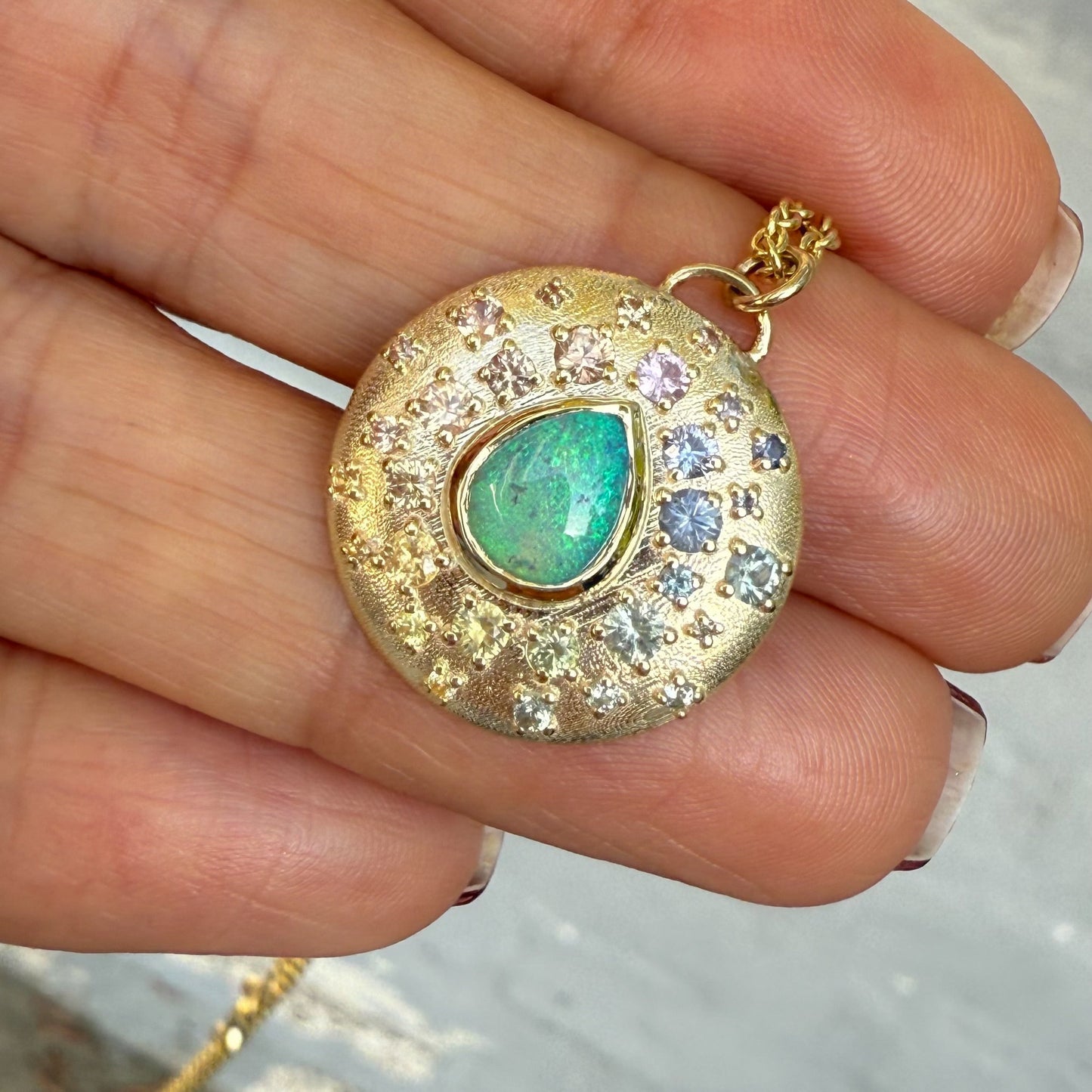 An Australian Opal Necklace by NIXIN Jewelry presents a contemporary opal pendant. In shade, its bezel set crystal opal appears predominantly green, yet flashes a full spectrum of color when in shifting light.