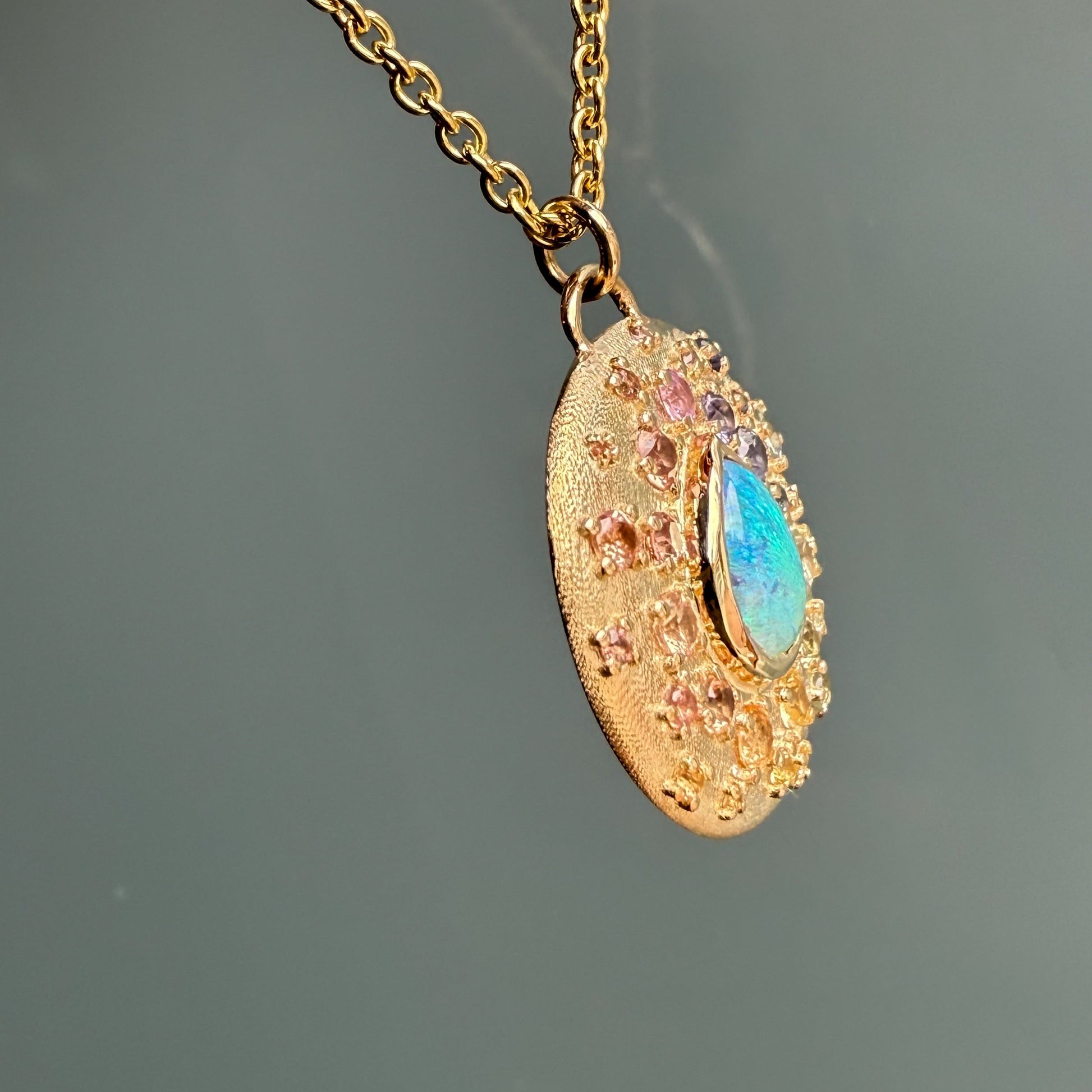 Side view of an Australian Opal Necklace by NIXIN Jewelry - a rare opal jewelry piece. Its natural opal is complemented by the colorful surrounding sapphires.