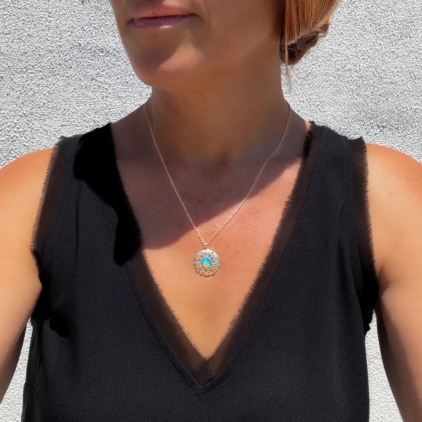A model wearing an Australian Opal Necklace by NIXIN Jewelry features a striking pear-shaped opal with a vivid pinfire pattern. Its fashion crystal opal necklace design presents a harmonious blend of colors.
