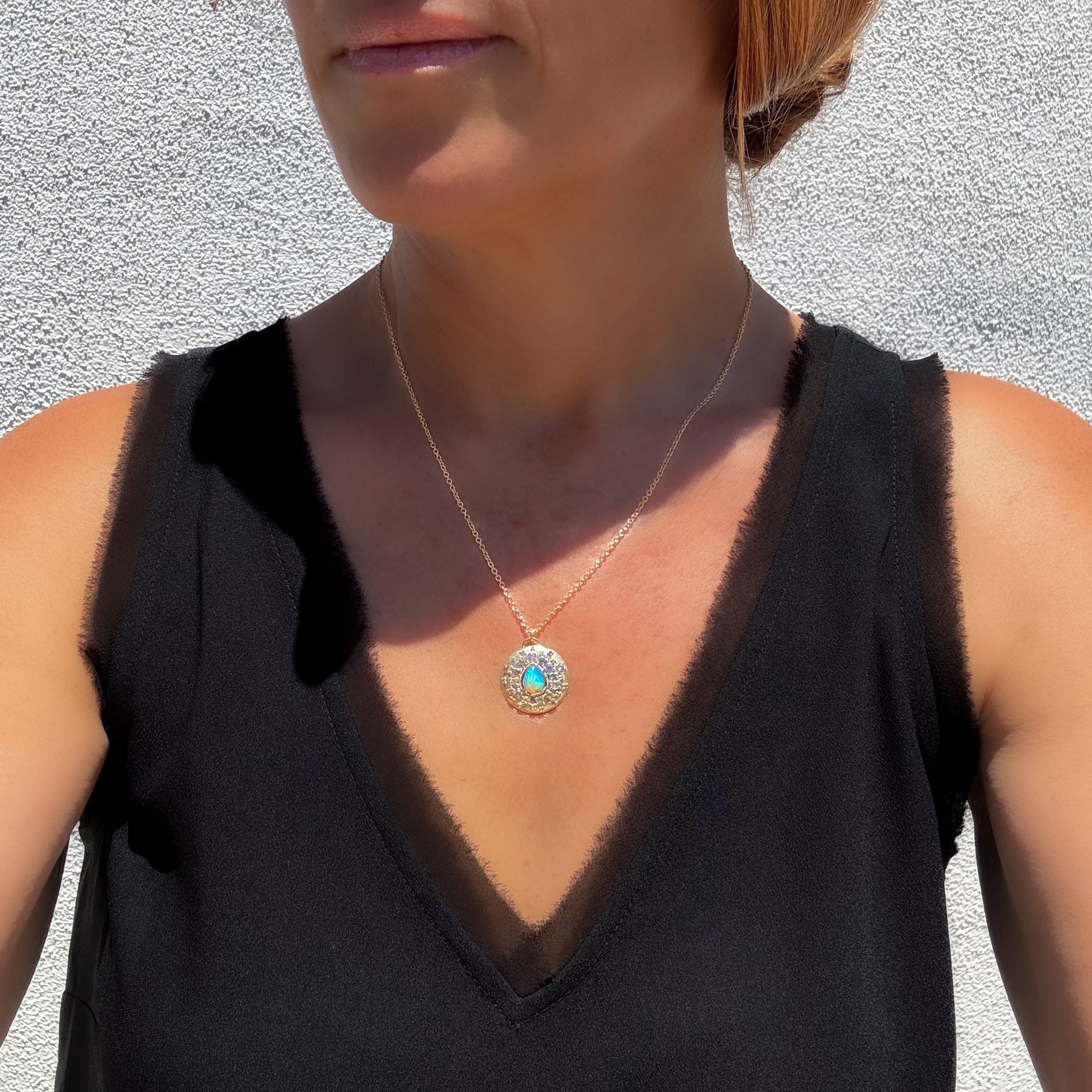 A model wearing an Australian Opal Necklace by NIXIN Jewelry features a striking pear-shaped opal with a vivid pinfire pattern. Its fashion crystal opal necklace design presents a harmonious blend of colors.