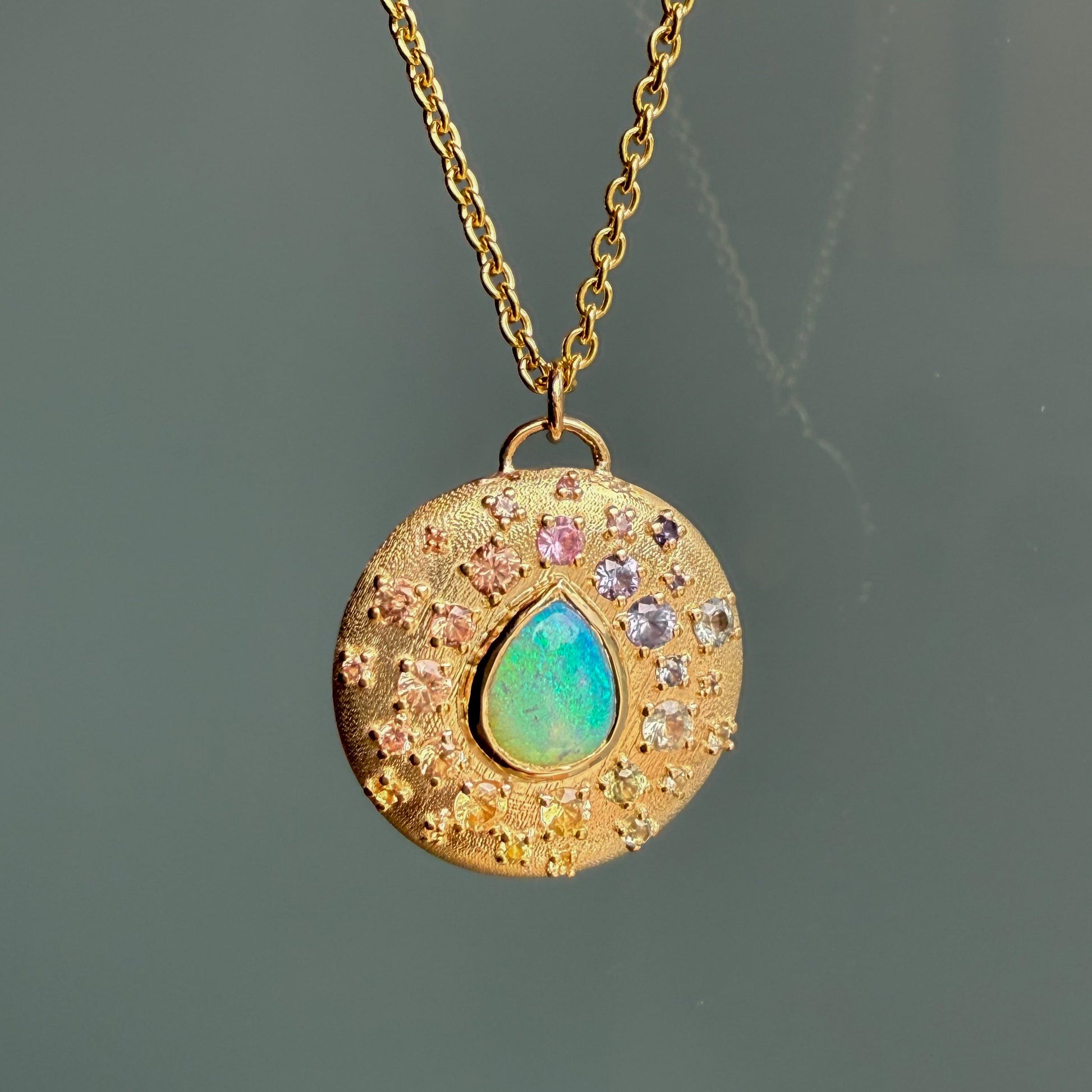 An Australian Opal Necklace by NIXIN Jewelry highlights a vivid crystal opal from Lightning Ridge. This unique opal necklace displays a stunning pinfire pattern with surrounding sapphires.