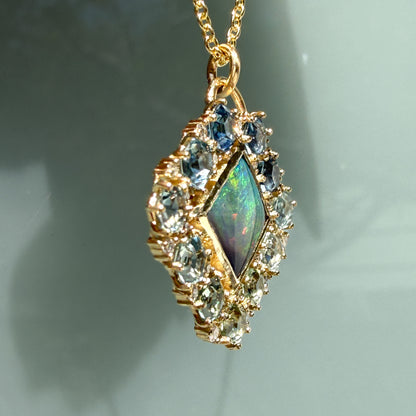 A profile shot captures the dimensional side view of an Australian Opal Pendant by NIXIN Jewelry. This perspective highlights the substantial thickness of the solid gold opal necklace framework and the secure prong settings across the sapphire necklace border. The clean, structured lines emphasize the exceptional craftsmanship behind this piece of luxury jewelry.