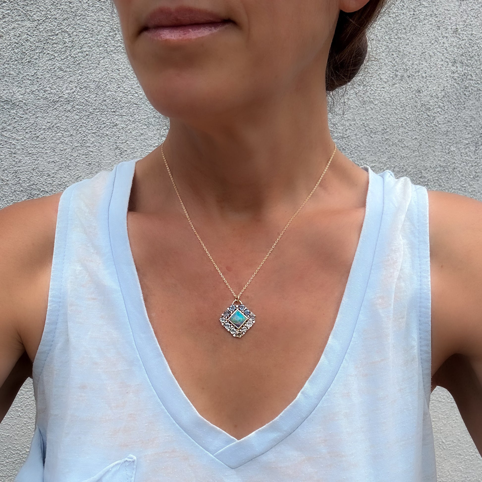 A model showcases an Australian Opal Pendant by NIXIN Jewelry. This women's luxury necklace serves as a premier example of unique fine jewelry that balances everyday elegance with high luxury. The vibrant australian opal centerpiece brings an artistic pop of color to the fine opal jewelry piece.