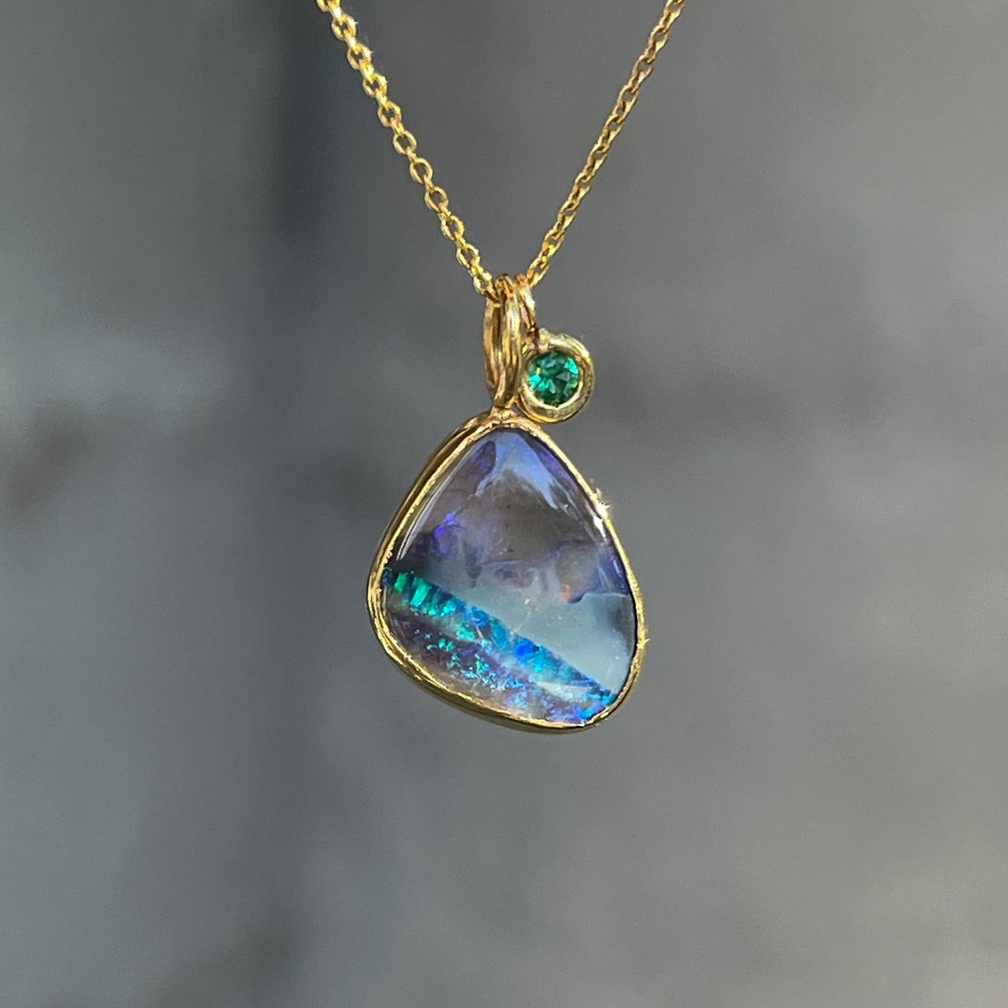 An Australian Opal Necklace by NIXIN Jewelry made in yellow gold with a small emerald and a black opal pendant.