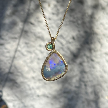 Back view of an Australian Opal Necklace by NIXIN Jewelry showing the open back of the bezel setting and the emerald stone charm.