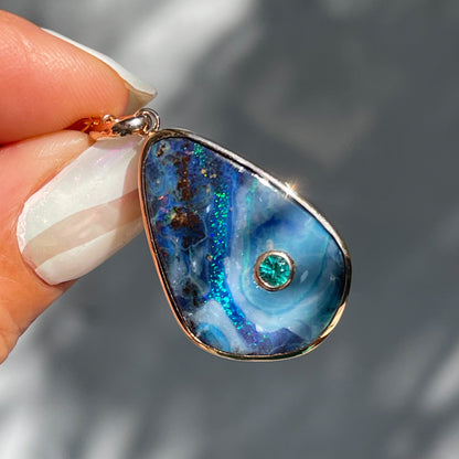 An Australian Opal Necklace by NIXIN Jewelry held in sunlight. An opal pendant necklace made in 14k rose gold.