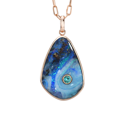 An Australian Opal Necklace by NIXIN Jewelry against a white background. The opal pendant is made in rose gold with a blue opal and an emerald.