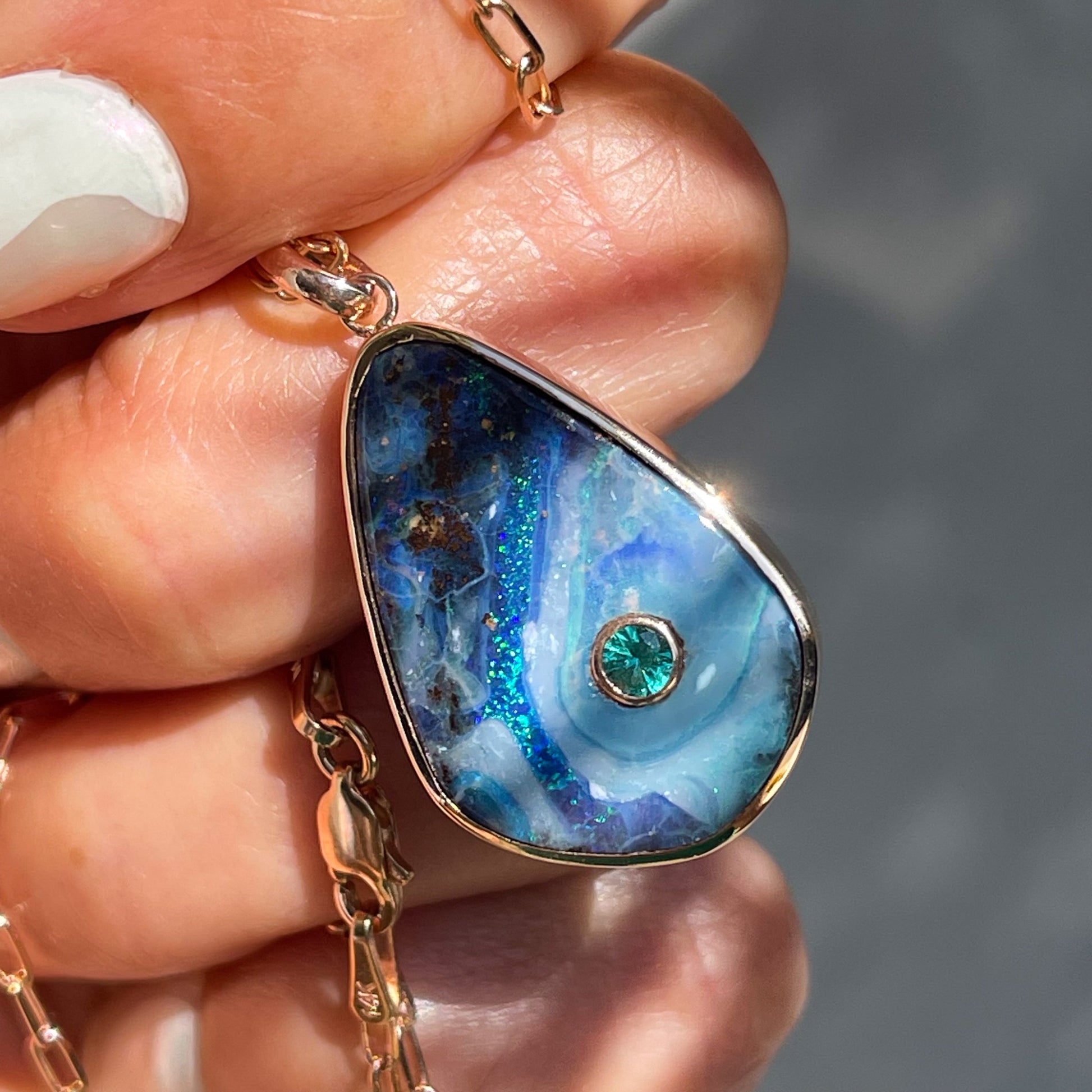 An Australian Opal Necklace by NIXIN Jewelry resting upon a hand. Available for purchase with other opal jewelry for sale at NIXINjewelry.com.