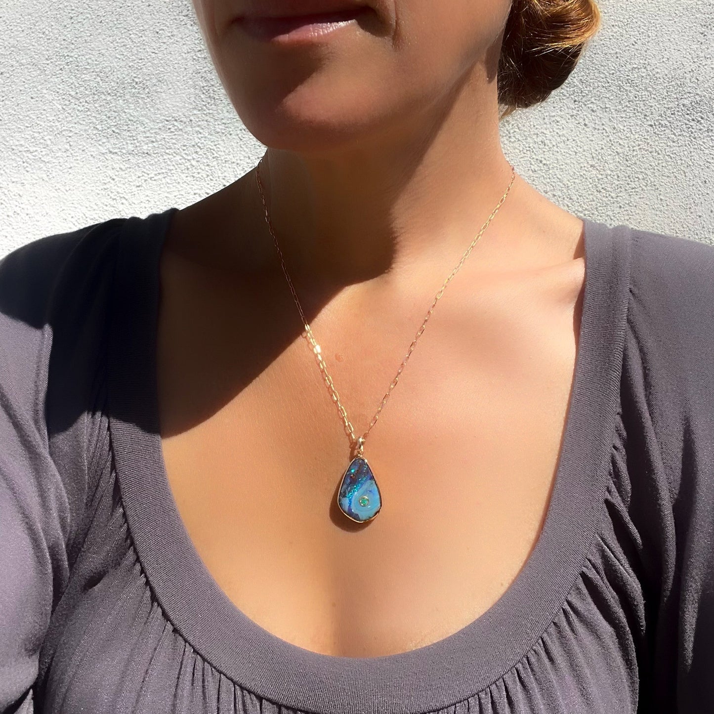 Model wearing an Australian Opal Necklace. Made in 14k rose gold with an emerald and Boulder Opal.