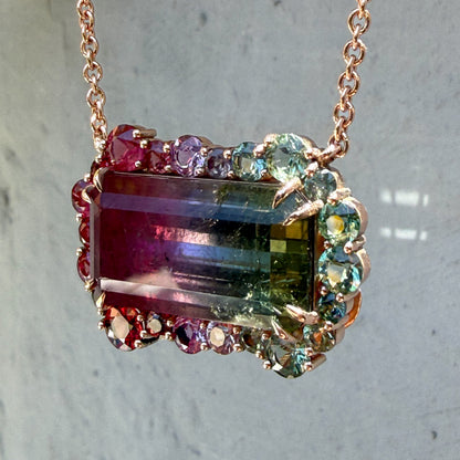 Sunlit, tilted view of the Empress Imbued Tourmaline Necklace by NIXIN Jewelry with dappled shadow accentuating the gemstone's natural inclusions.