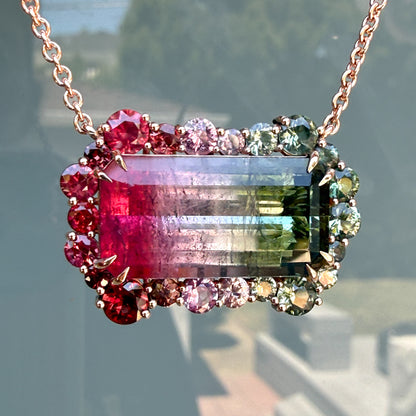 Empress Imbued Tourmaline Necklace by NIXIN Jewelry in 14K rose gold, a watermelon tourmaline framed by a ruby, pink sapphire, and green sapphire halo.