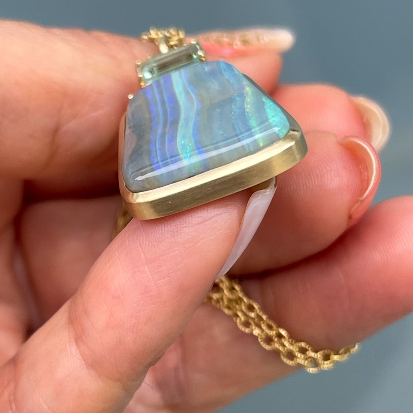 An Australian Opal Necklace by NIXIN Jewelry shown from the end to display the clean bezel setting of the blue opal.