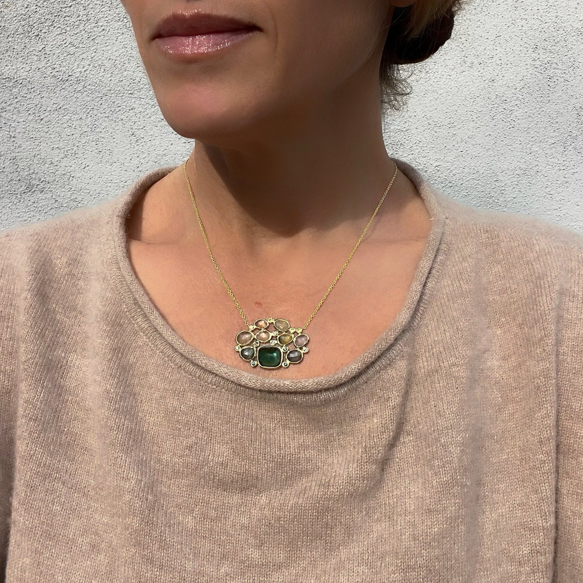  Model wearing a Tourmaline and Sapphire Necklace by NIXIN Jewelry with green gemstones set in 14k gold.