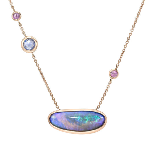 An Australian Opal Necklace by NIXIN Jewelry features a horizontal boulder opal pendant set in polished rose gold. This unique opal necklace is distinguished by three asymmetrical sapphires placed along the delicate chain, making it a distinct piece of unique jewelry.