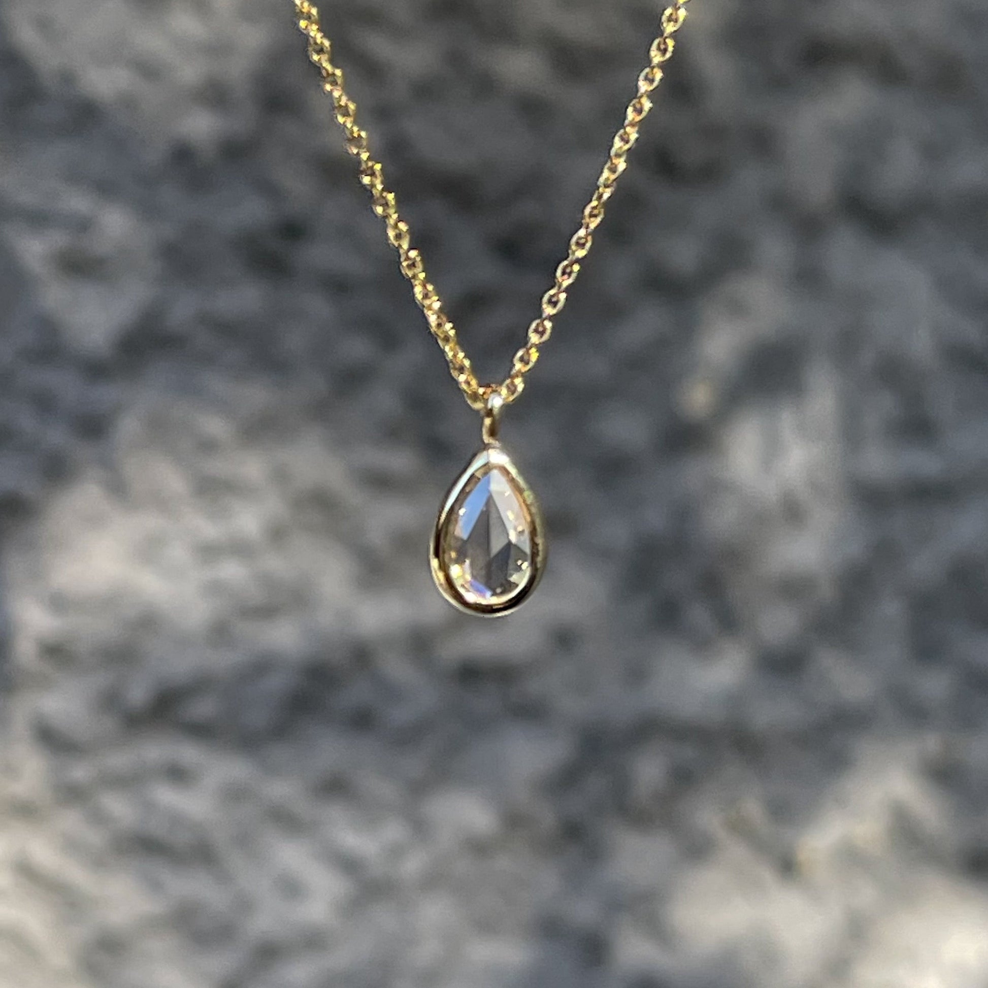 A Dainty Diamond Necklace by NIXIN Jewelry with a pear shaped diamond in yellow gold.