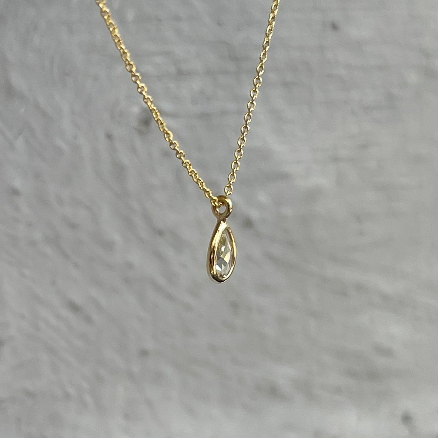 Side view of a Dainty Diamond Necklace by NIXIN Jewelry with a pear shaped diamond pendant.