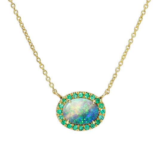 This is an Australian Opal Necklace by NIXIN Jewelry featuring a rare Lightning Ridge black crystal opal set in 14k gold. The luxury necklace showcases a natural opal with an emerald halo in a delicate prong setting. This unique fine jewelry is for the discerning collector of rare opal necklaces.
