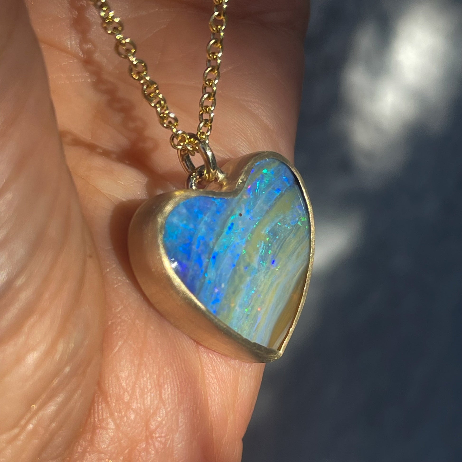 Side view of an Australian Opal Necklace by NIXIN Jewelry with a Boulder Opal set in 14k gold.