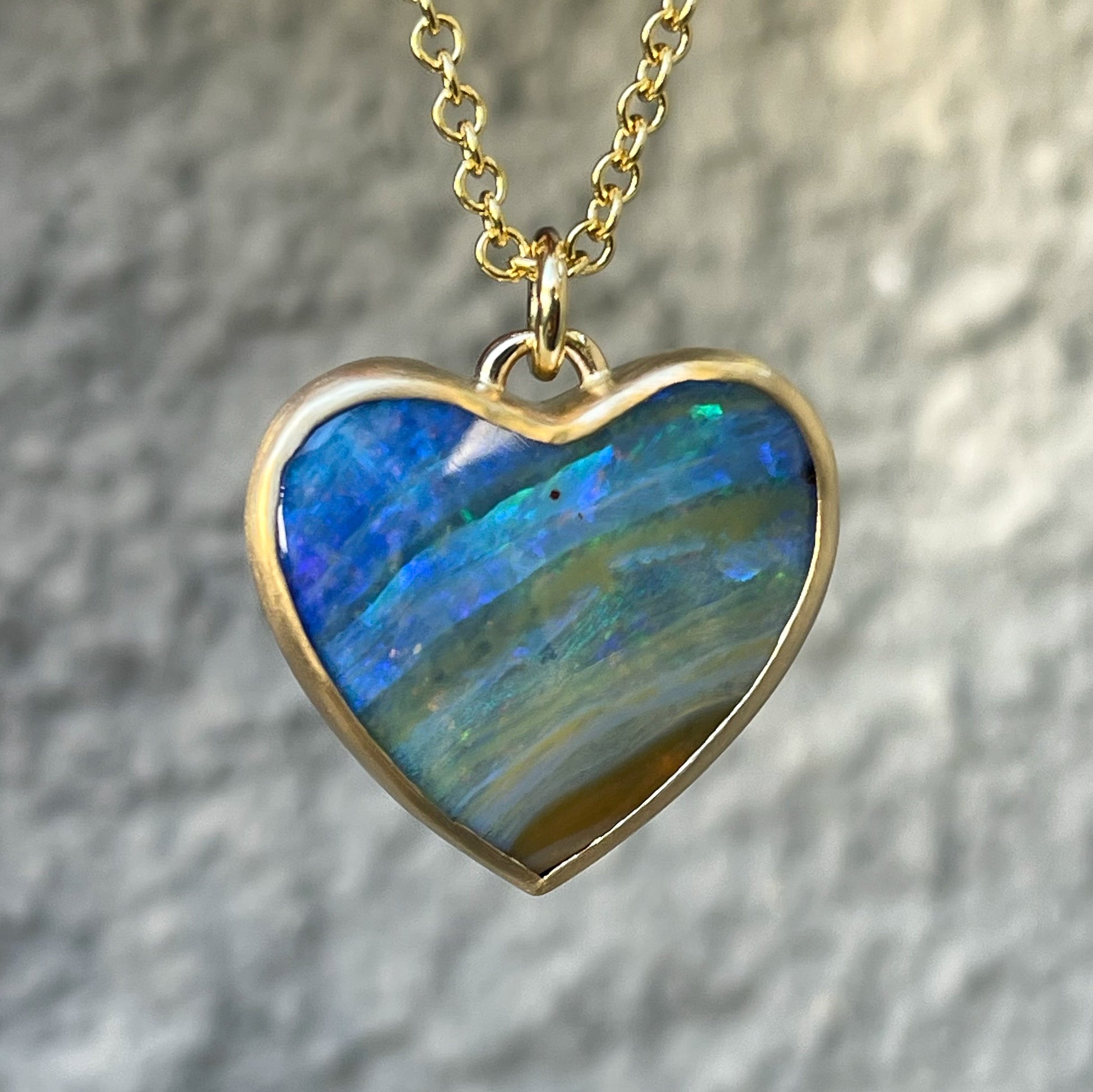 An Australian Opal Necklace by NIXIN Jewelry made in gold with a blue opal in a bezel setting.