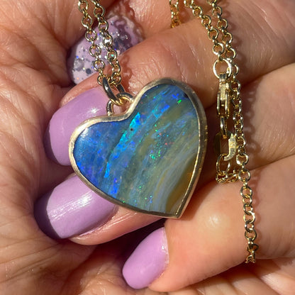 An Australian Opal Necklace by NIXIN Jewelry with an opal heart in a handmade gold setting.