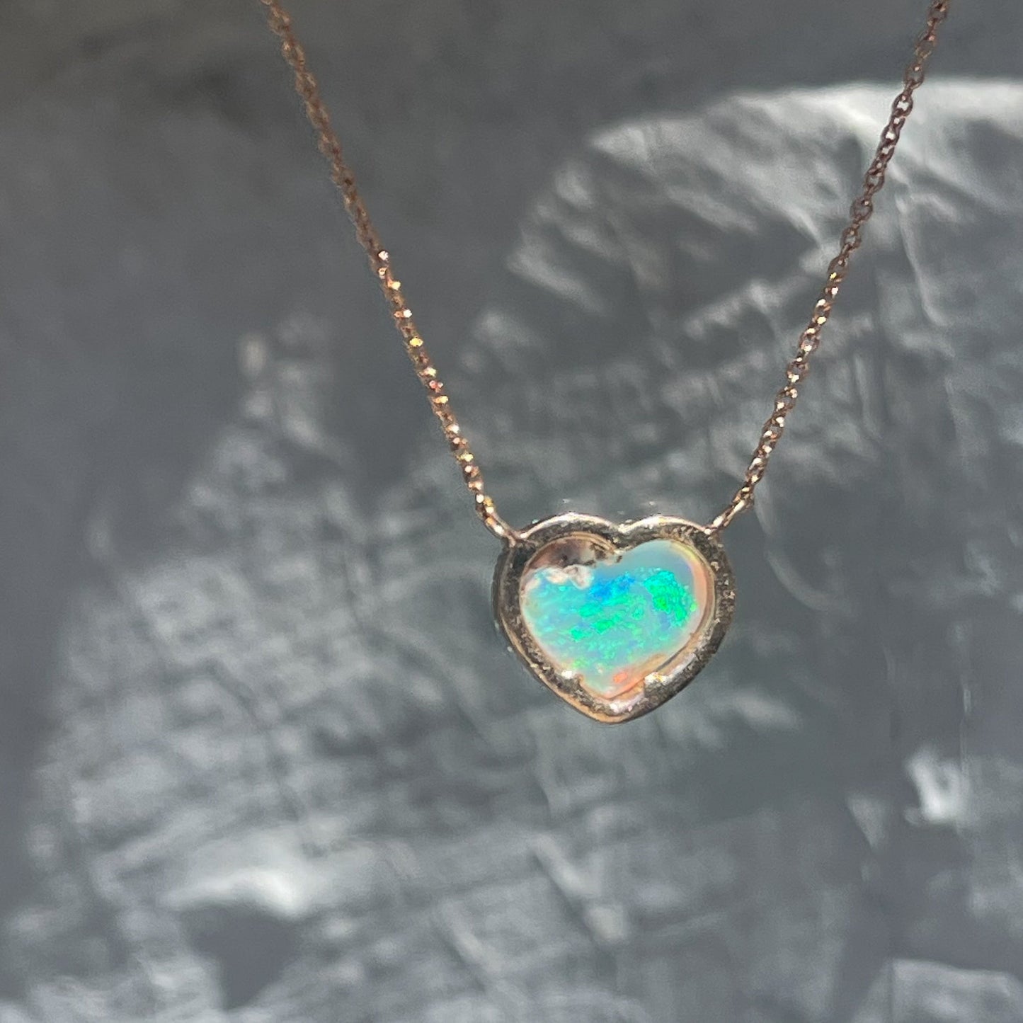 Back view of an Opal Heart Necklace by NIXIN Jewelry. The opal is set in rose gold and hangs from an Italian chain.