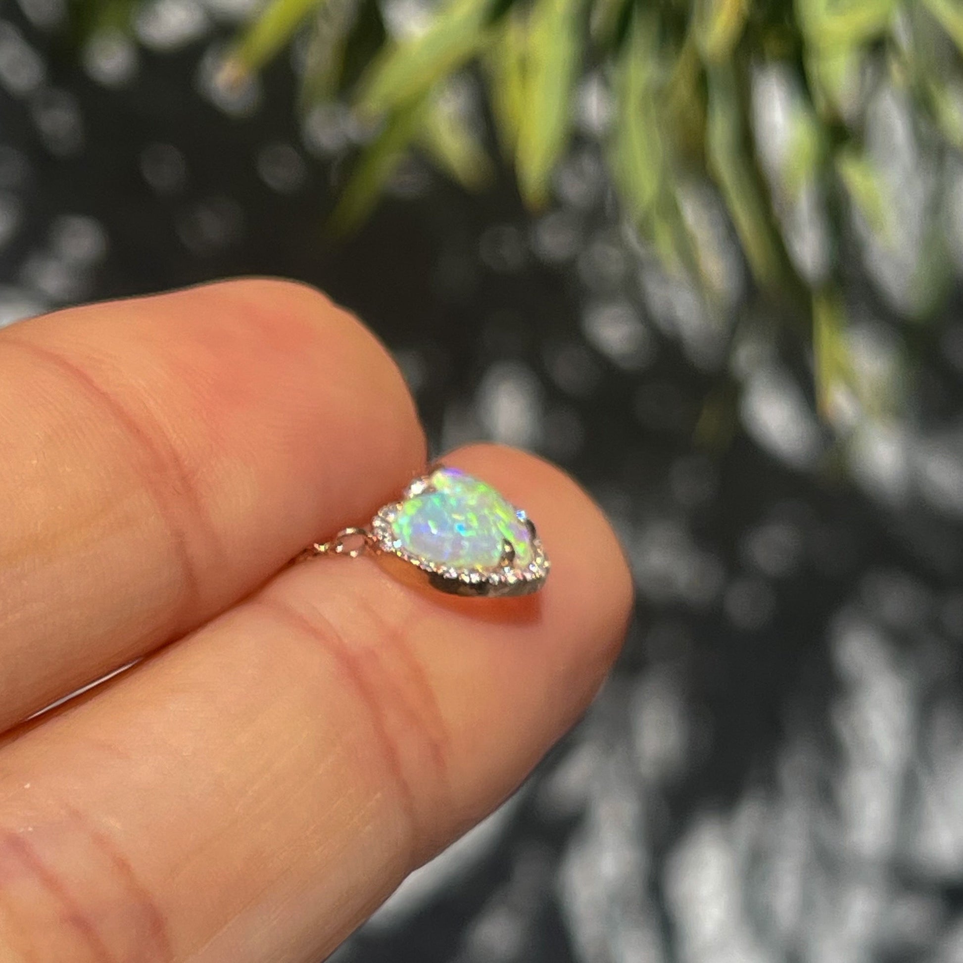 Profile shot of an Opal Heart Necklace by NIXIN Jewelry. The dainty opal necklace is made with rose gold and tiny diamonds.