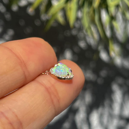 Profile shot of an Opal Heart Necklace by NIXIN Jewelry. The dainty opal necklace is made with rose gold and tiny diamonds.