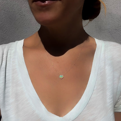 An Opal Heart Necklace by NIXIN Jewelry worn by a model to show scale. The opal necklace is among the opal jewelry for sale on the NIXIN Jewelry website.