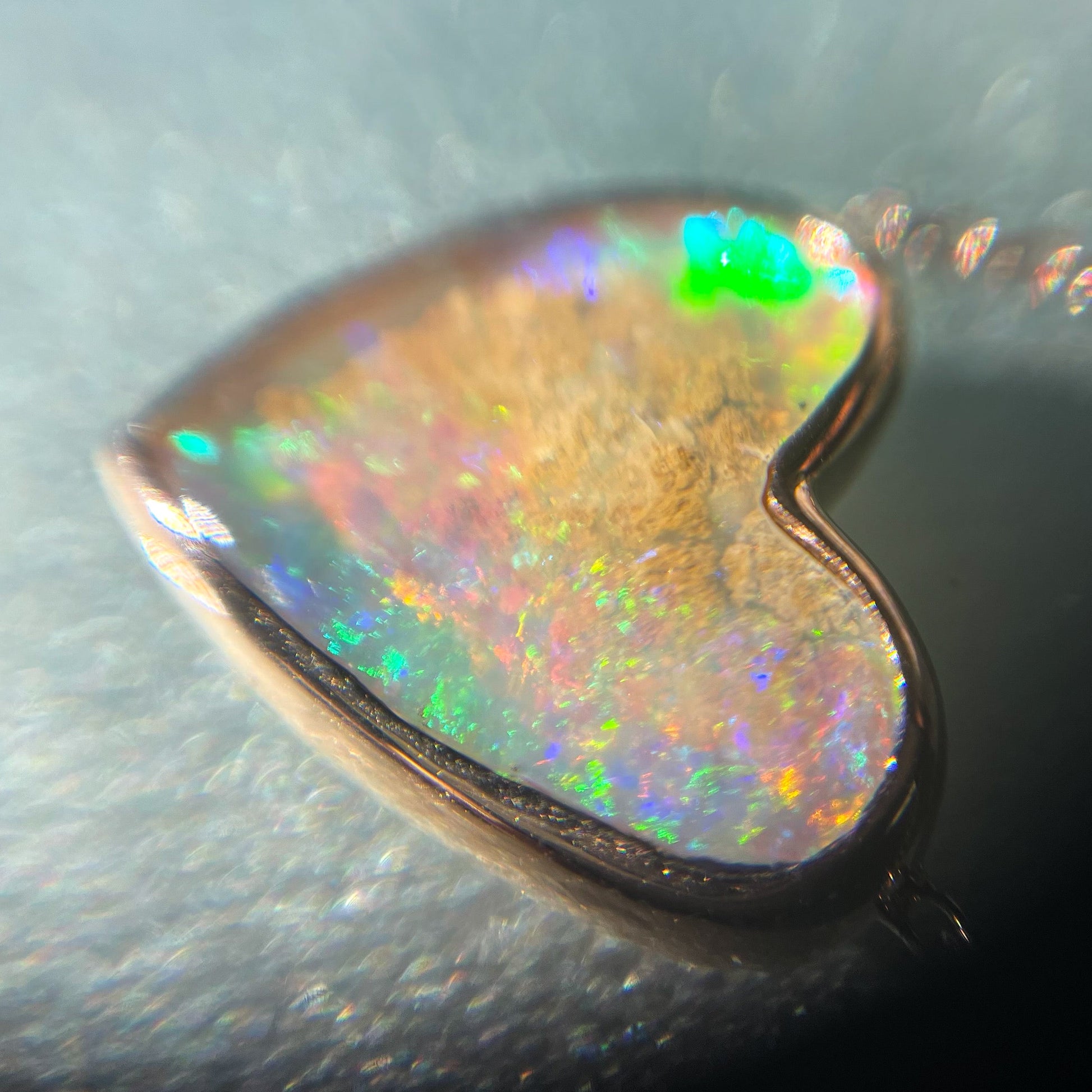 Magnified shot of an Australian Opal Necklace by NIXIN Jewelry with an opal heart set in rose gold.