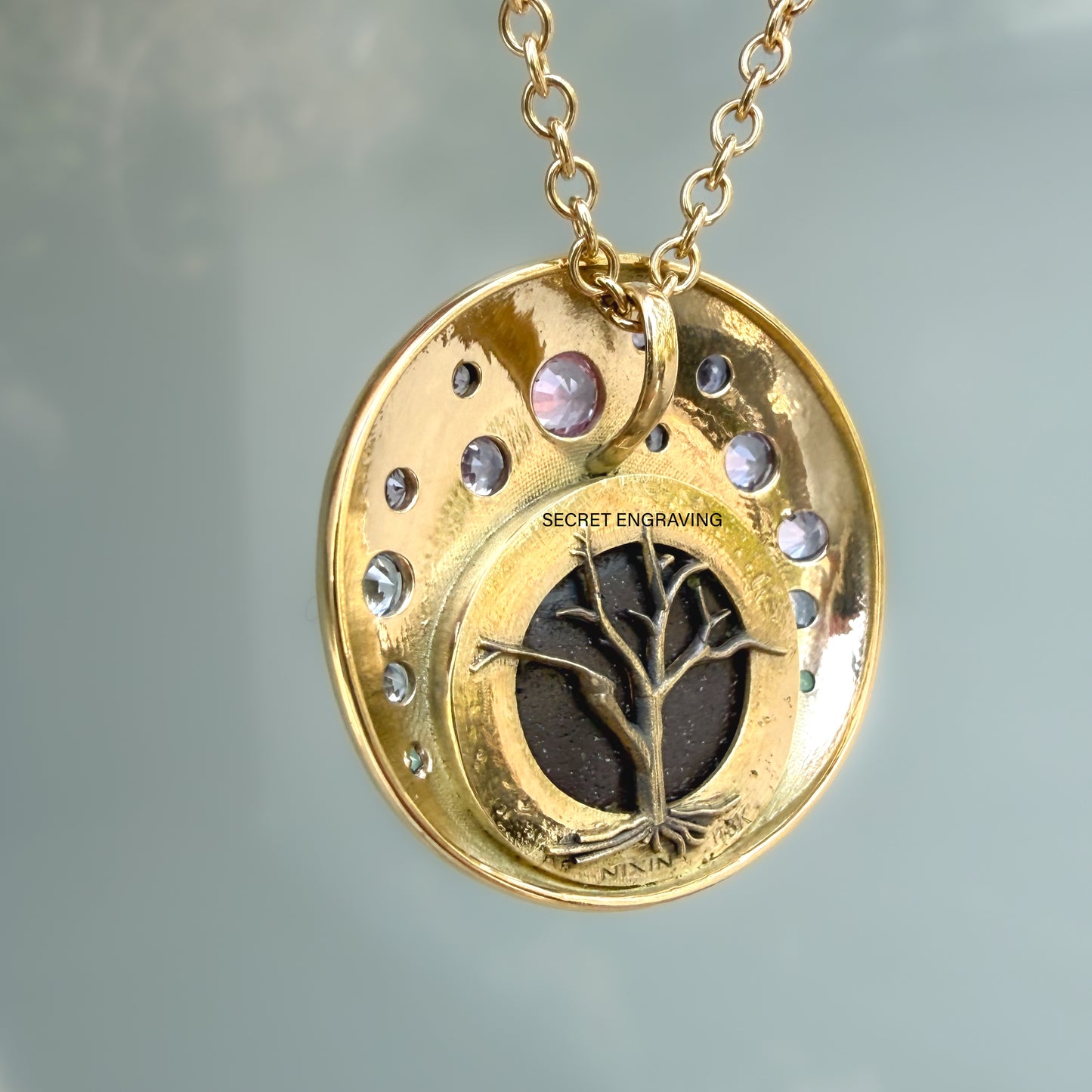 This photograph displays the detailed back view of an Australian Opal Pendant by NIXIN Jewelry. This unique fine jewelry piece is a stunning example of jewelry art, featuring an intricate gold tree motif with exposed roots set against the boulder opal ironstone. The 18k gold necklace hangs gracefully, showcasing the precise crafting of this women's luxury necklace.