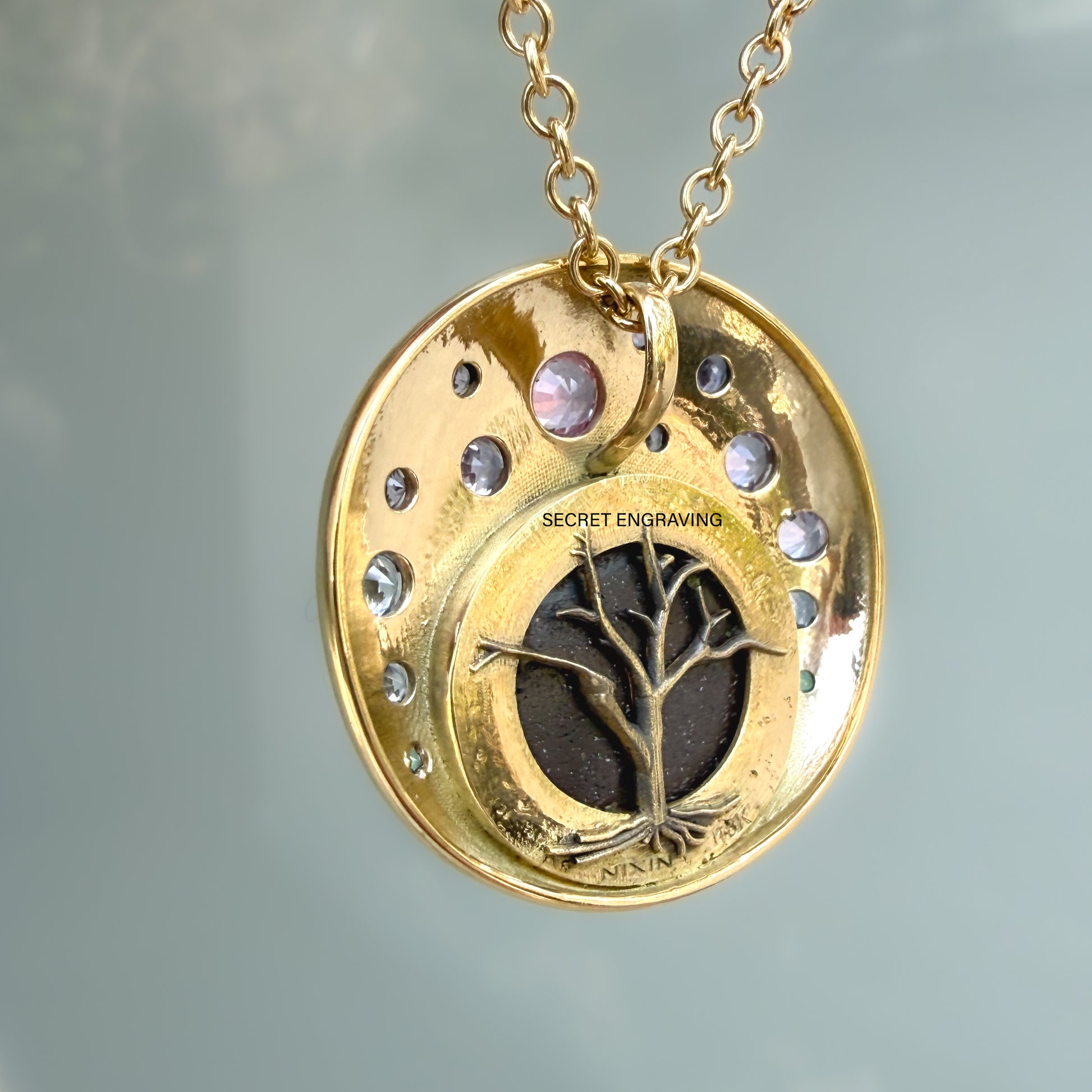 This photograph displays the detailed back view of an Australian Opal Pendant by NIXIN Jewelry. This unique fine jewelry piece is a stunning example of jewelry art, featuring an intricate gold tree motif with exposed roots set against the boulder opal ironstone. The 18k gold necklace hangs gracefully, showcasing the precise crafting of this women's luxury necklace.