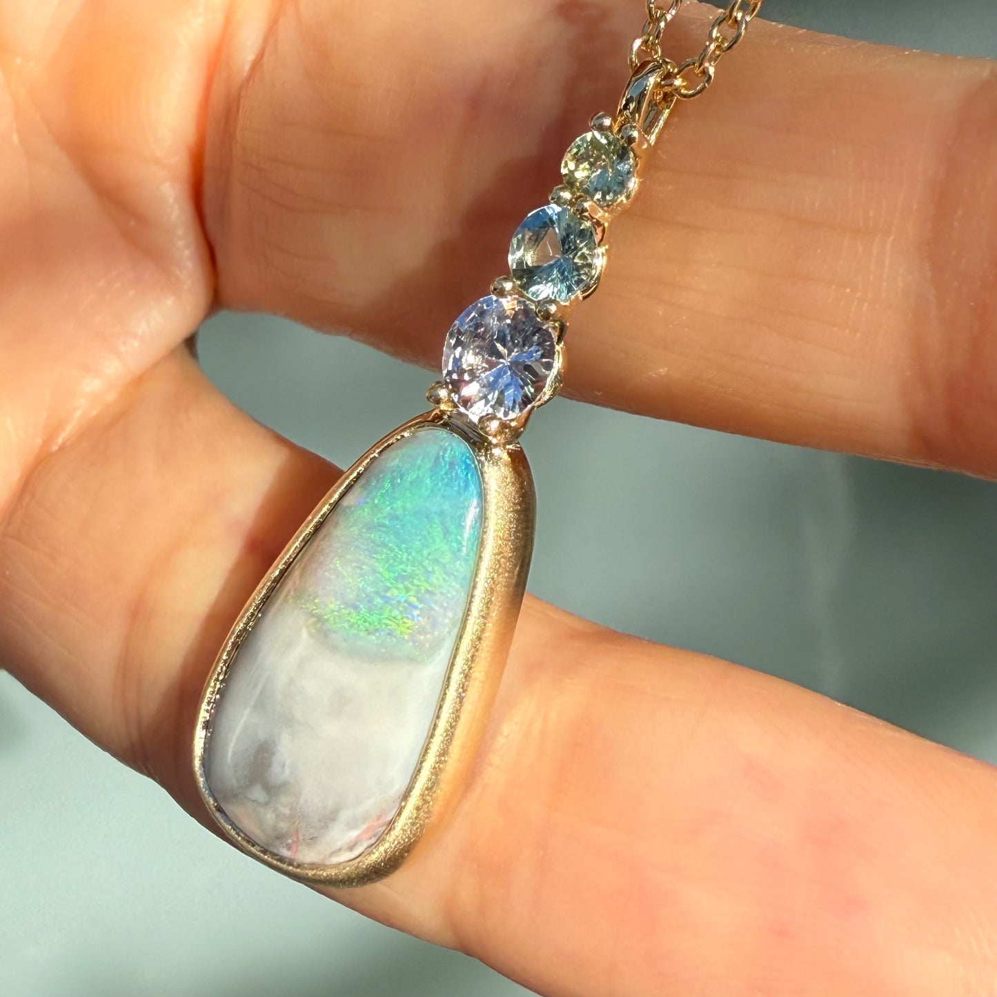 An Australian Opal Necklace by NIXIN Jewelry where the natural opal flashes brilliant greens and blues, secured in a substantial bezel setting. This piece is the epitome of jewelry art, offering true unique fine jewelry value.