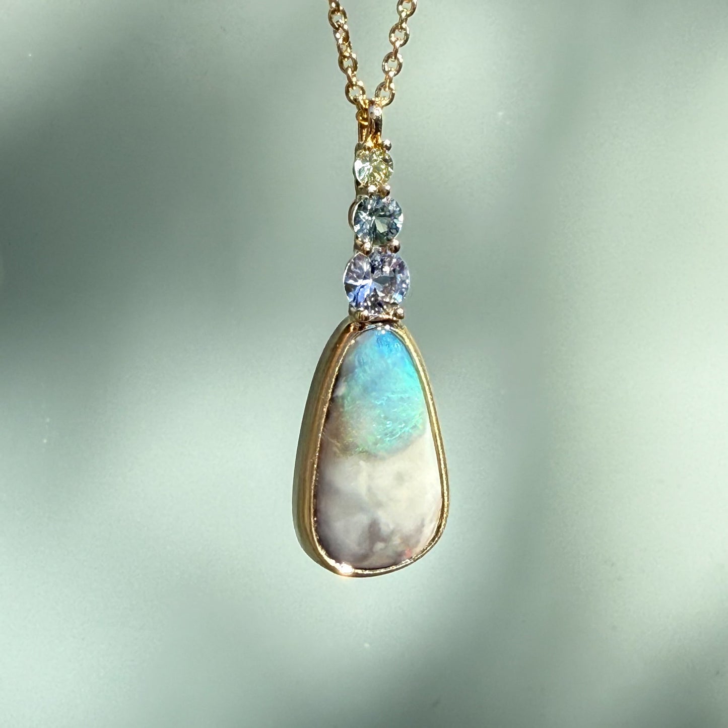An Australian Opal Necklace by NIXIN Jewelry crafted in matte gold showcasing a breathtaking natural opal with intense fire. The elegant pendant design emphasizes jewelry art for the discerning buyer seeking rare jewelry.