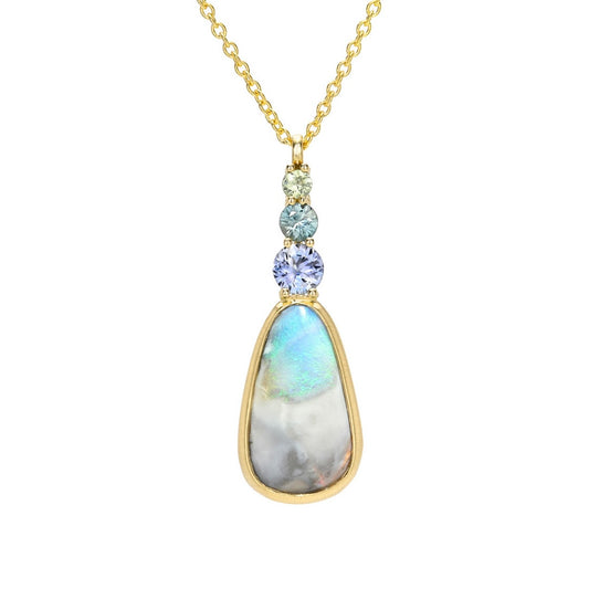An Australian Opal Pendant by NIXIN Jewelry featuring a vibrant blue opal set in a modern bezel setting. This unique fine jewelry piece is complemented by a delicate row of ombré sapphires, defining it as a women's luxury necklace.