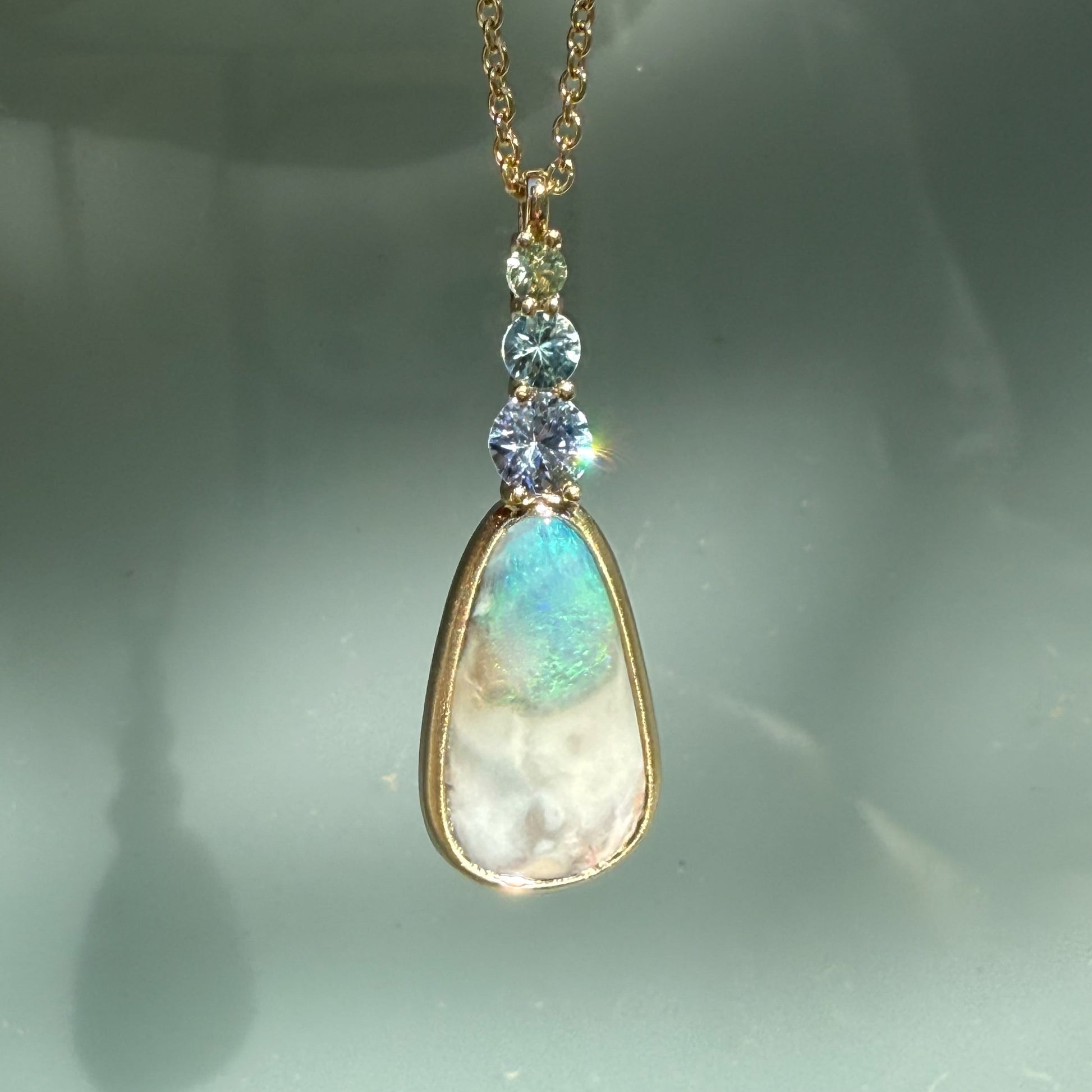 An Australian Opal Pendant by NIXIN Jewelry with a spectacular natural opal showcasing deep color that suggests the "ancient sea." The opal nests in a gold bezel setting, securing this rare opal jewelry.