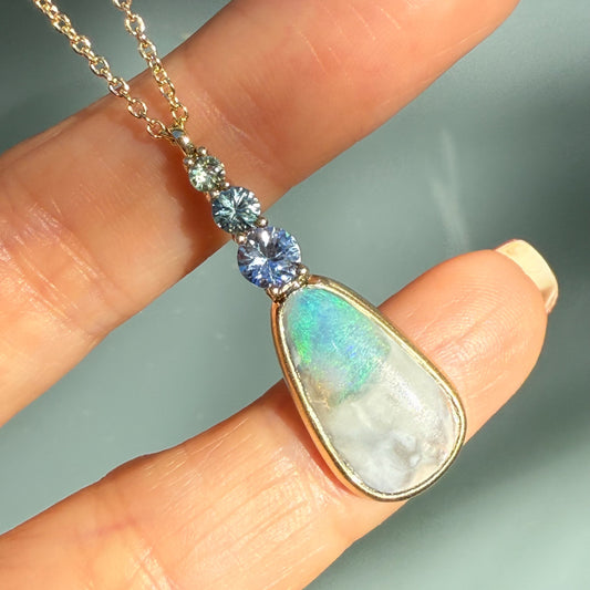 An Australian Opal Necklace by NIXIN Jewelry featuring a stunning blue opal centerpiece, accented by subtle sapphires. This women's luxury necklace is crafted with exceptional art and high-grade materials.