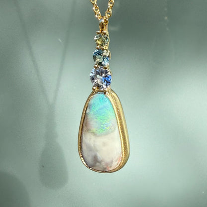 An Australian Opal Pendant by NIXIN Jewelry in a sleek, matte finish gold setting, ensuring the focus remains on the natural opal gemstone. The combination of rare opal jewelry and modern design targets the luxury necklace market.