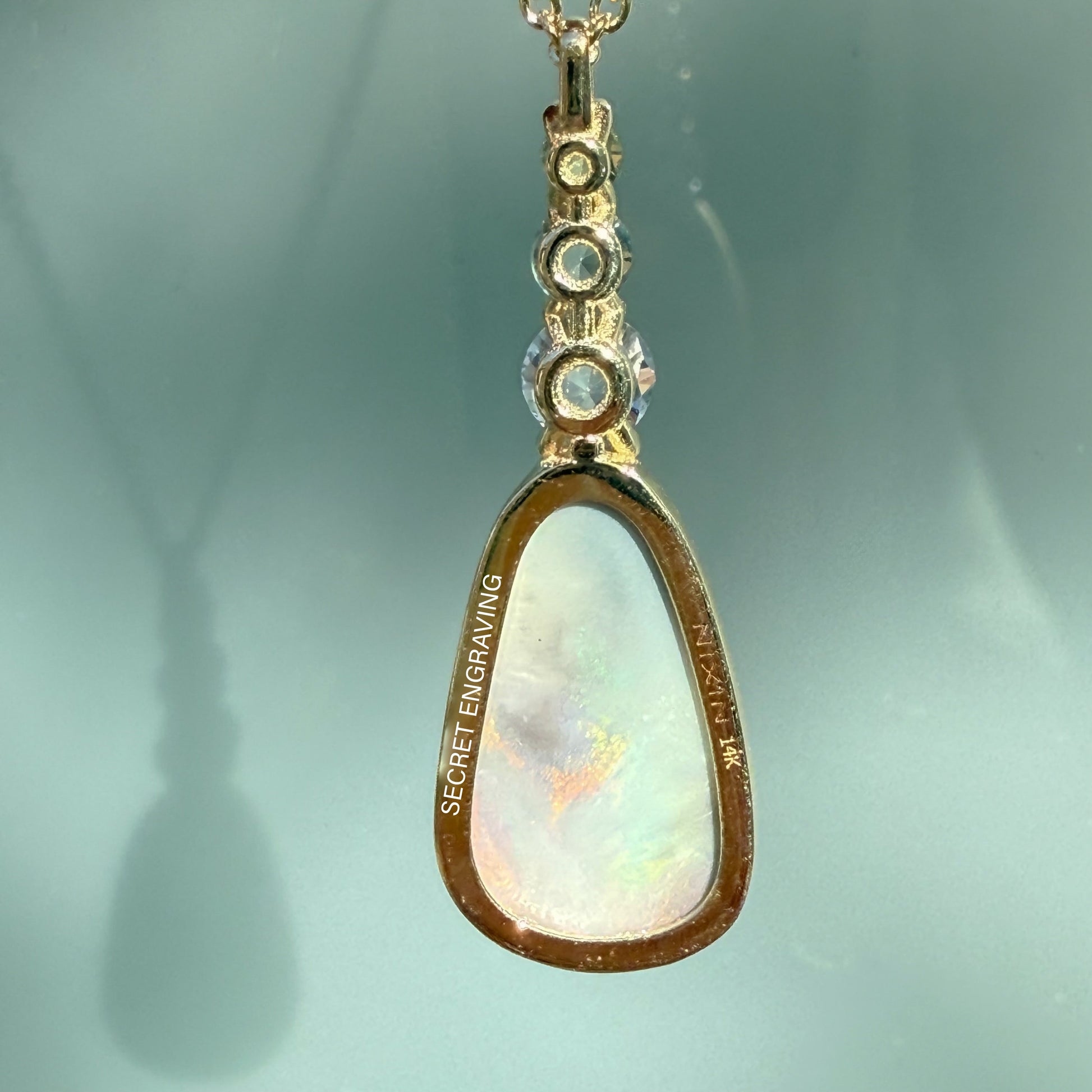 An Australian Opal Pendant by NIXIN Jewelry showcases a mesmerizing natural opal centerpiece set in a sleek, bezel setting. This rare opal jewelry piece is accented by vibrant ombré sapphires, defining it as unique fine jewelry for the luxury necklace market. Crafted in matte gold, this exclusive design embodies jewelry art for discerning clients seeking women's luxury necklace sophistication.