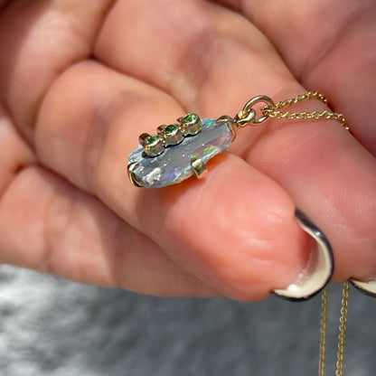 Side view of an Australian Opal Necklace by NIXIN Jewelry with a Black Opal and green gemstones. 